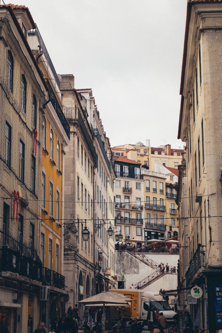 A street in central Lisbon with yellow buildings and a view up the hill